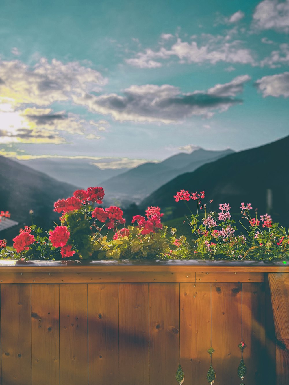 a wooden fence with flowers and mountains in the background