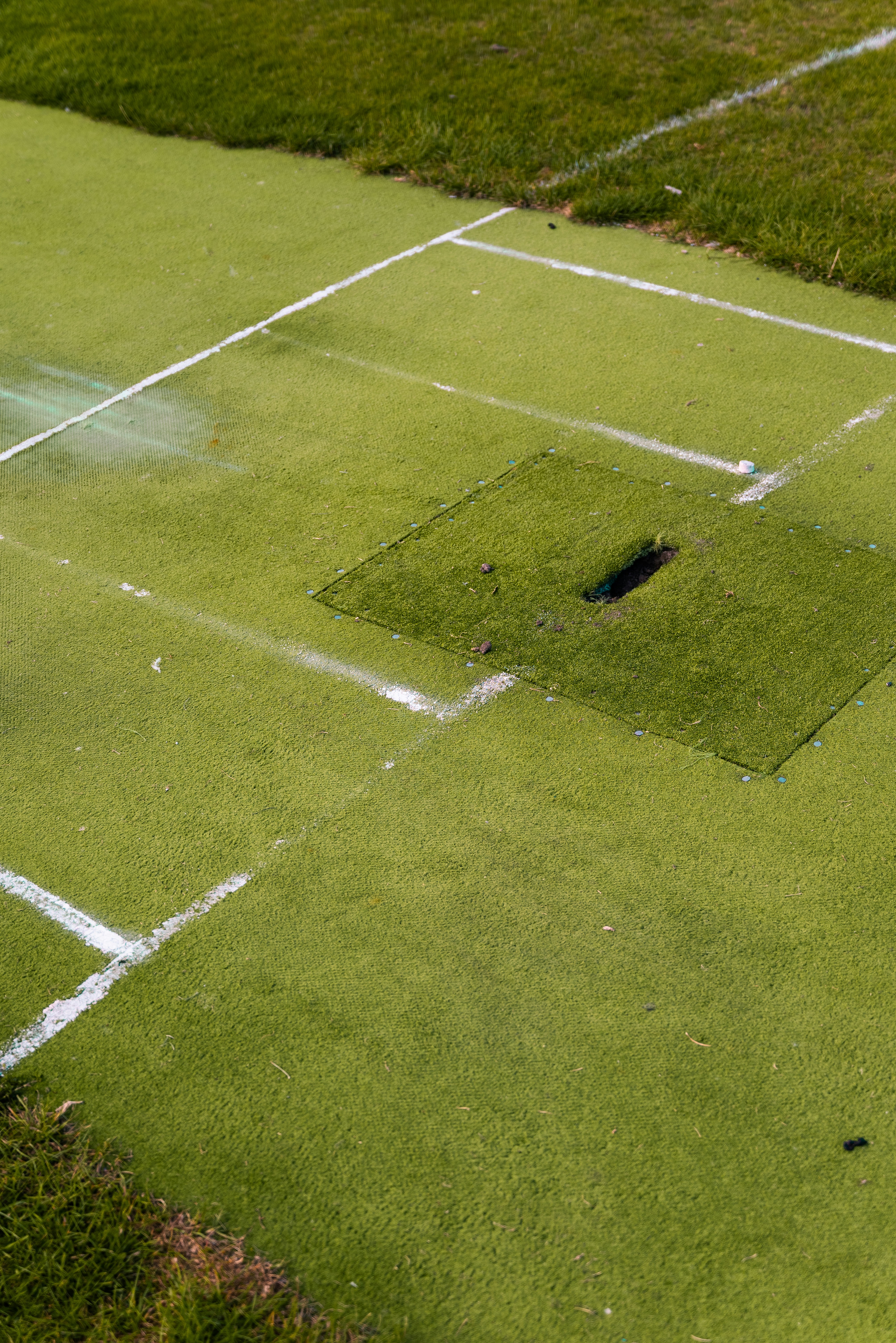 Green artificial turf sports field with white boundary lines.