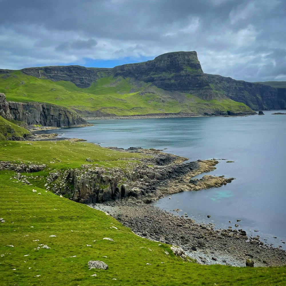 a body of water with grass and hills around it