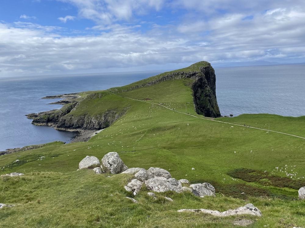 a grassy hill with a body of water in the background