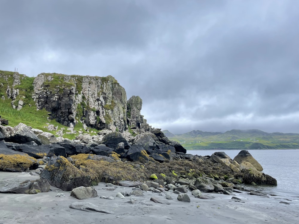 a rocky beach with a cliff and water in the background