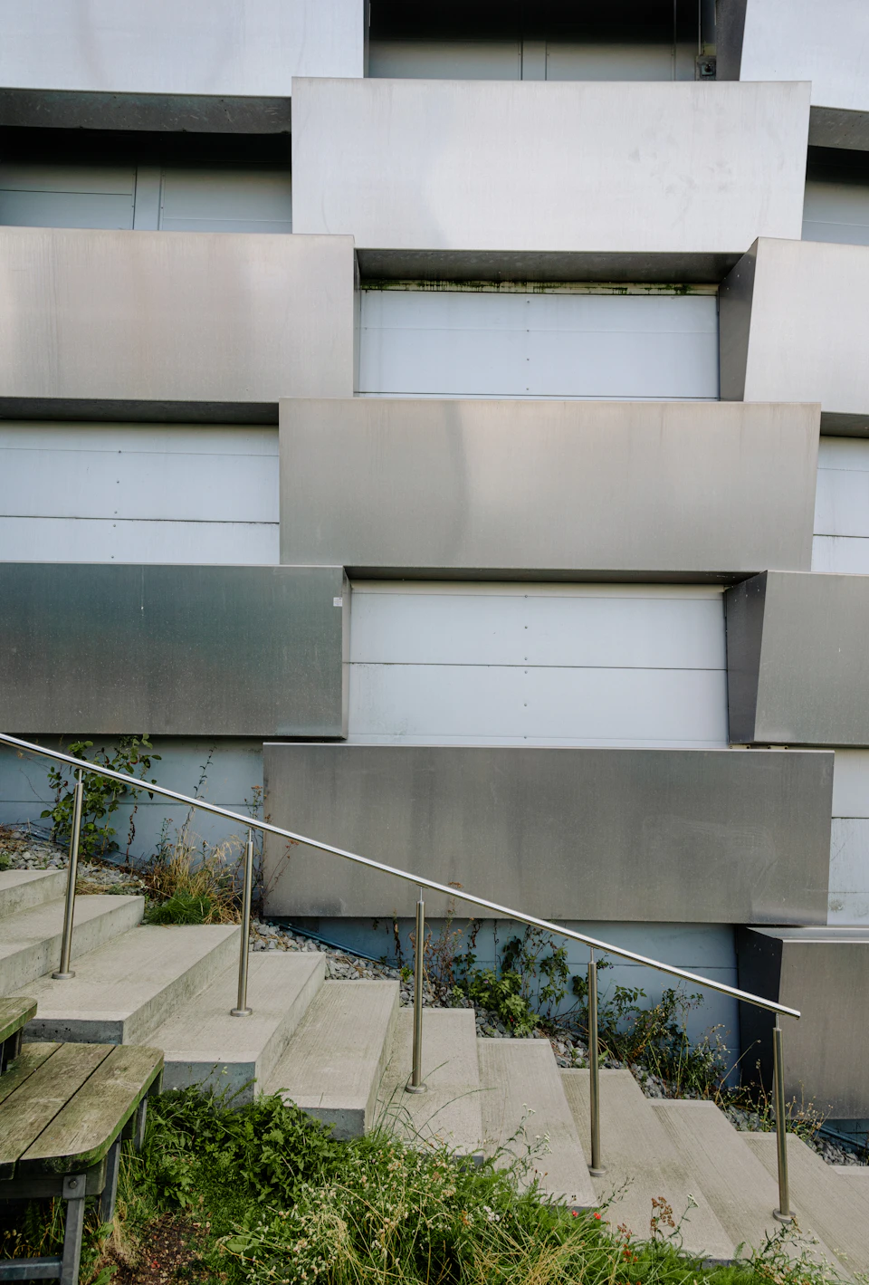 Modern building features stacked windows and doors with contrasting gray concrete and white facade