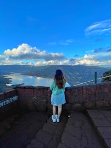 a woman standing on a ledge overlooking a city