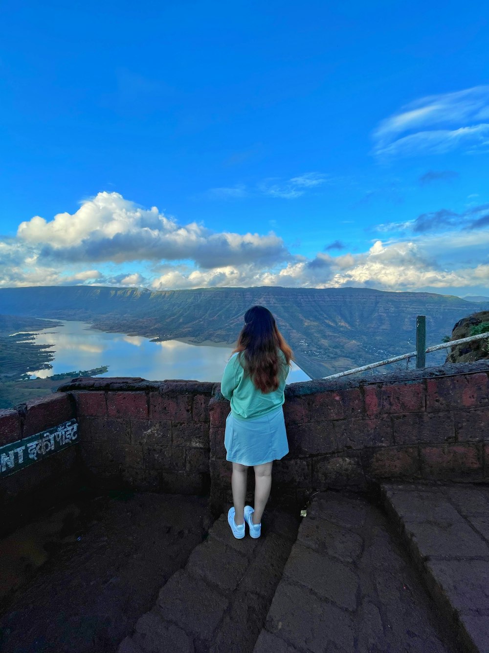 a woman standing on a ledge overlooking a city