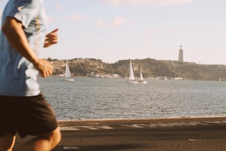 Athlete wearing smart sunglasses jogging along a sunny waterfront path.
