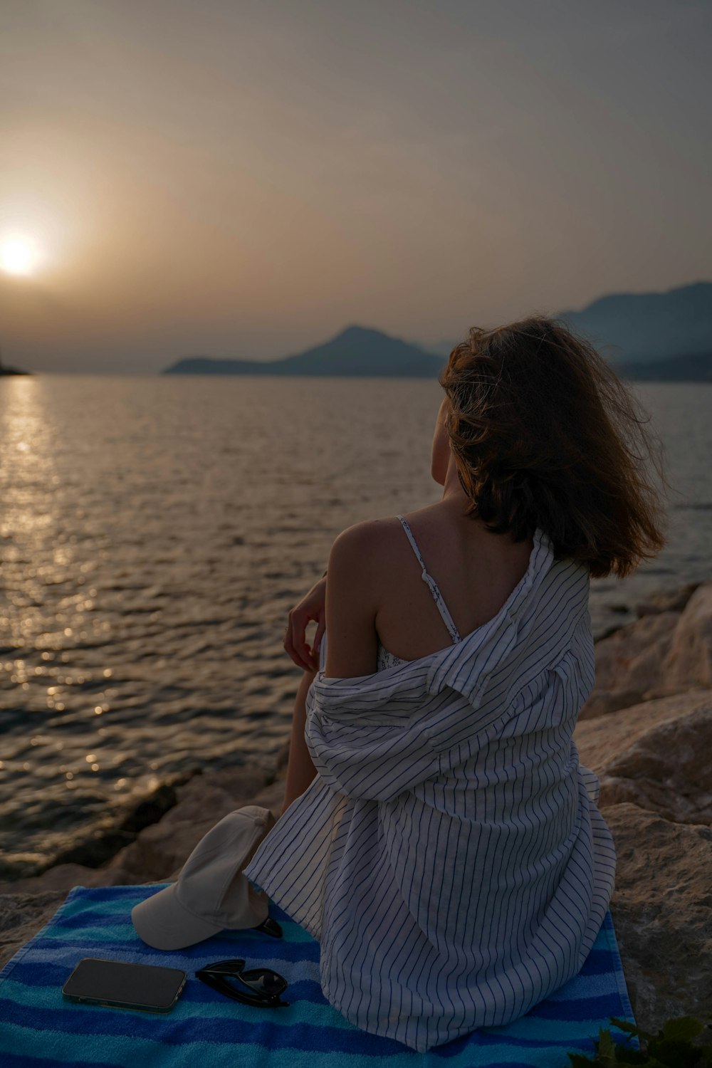 a person sitting on a rock looking out at the water