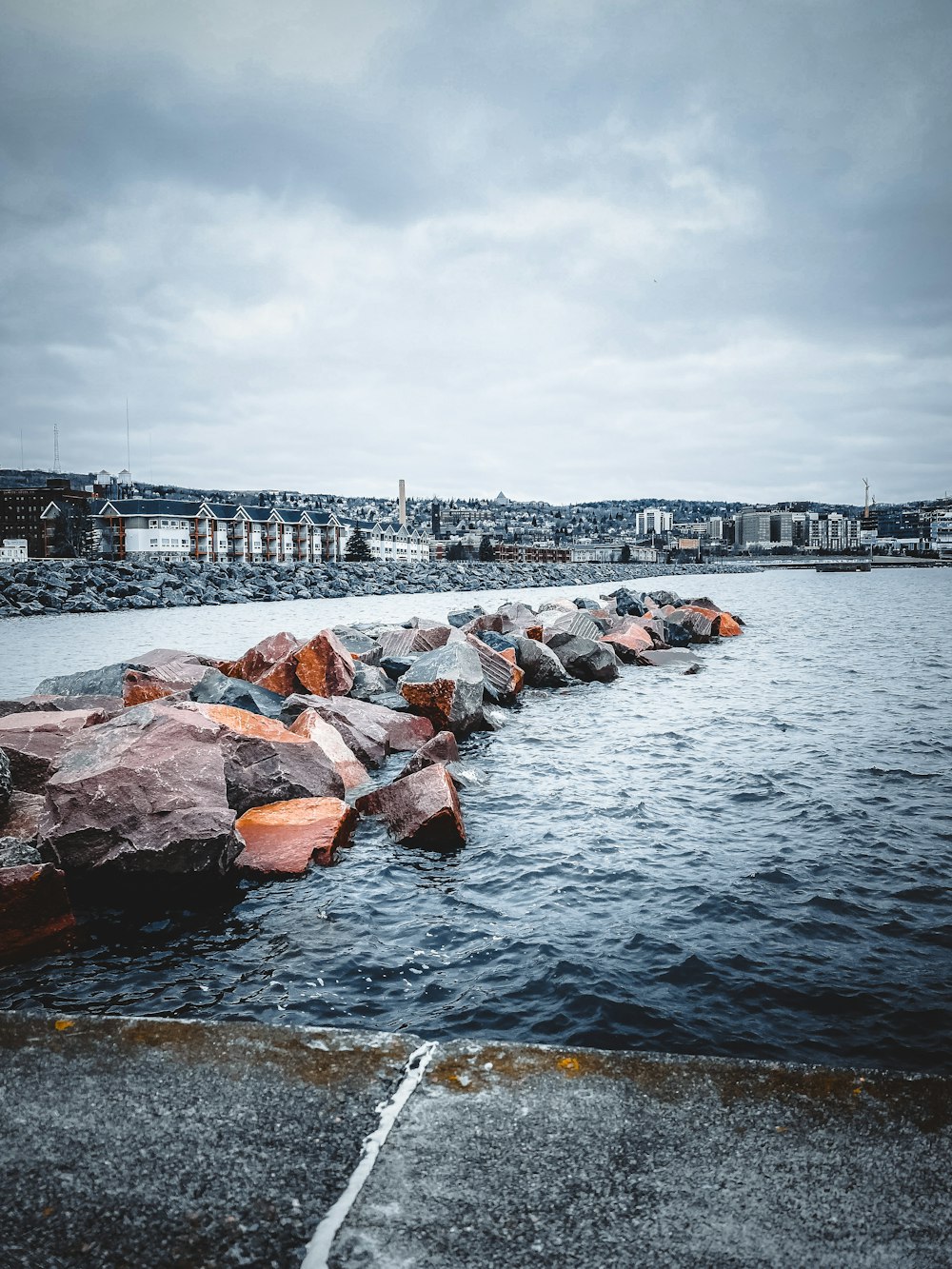 a rocky beach with buildings in the background