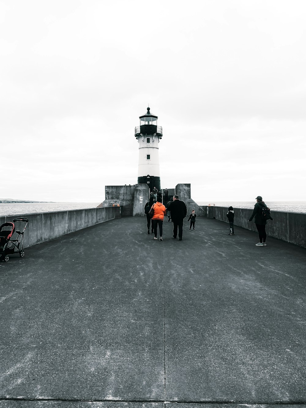 a group of people walking on a concrete walkway by a lighthouse