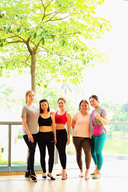 a group of women posing for a photo under a tree