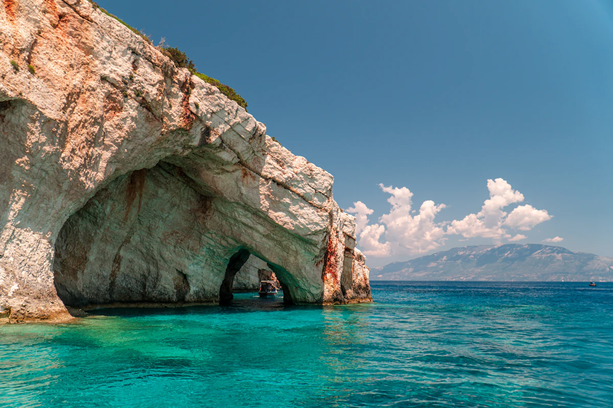 Boat passing through a natural stone archway in the Blue Caves of Zakynthos