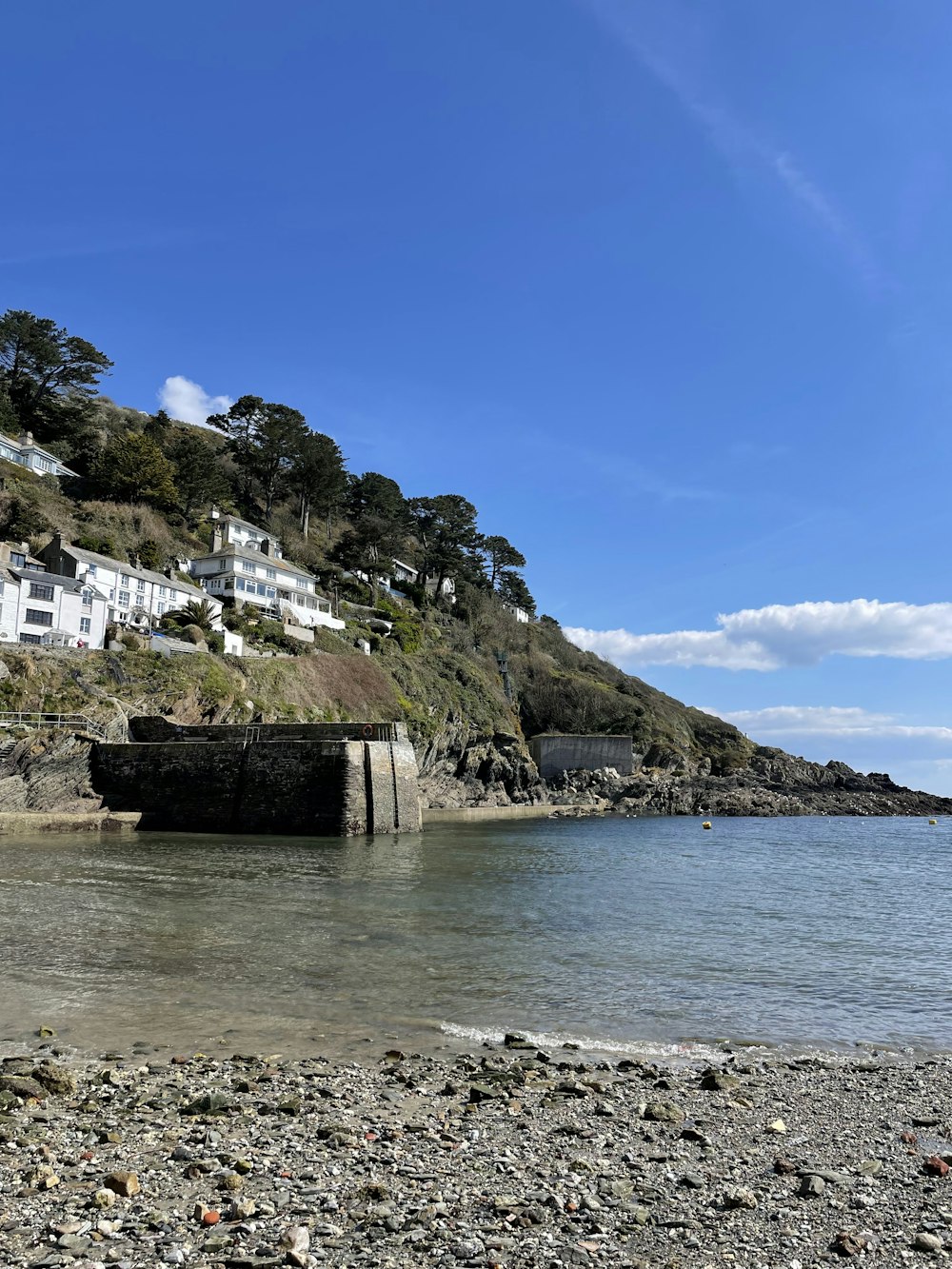 a rocky beach with a cliff and houses on the other side