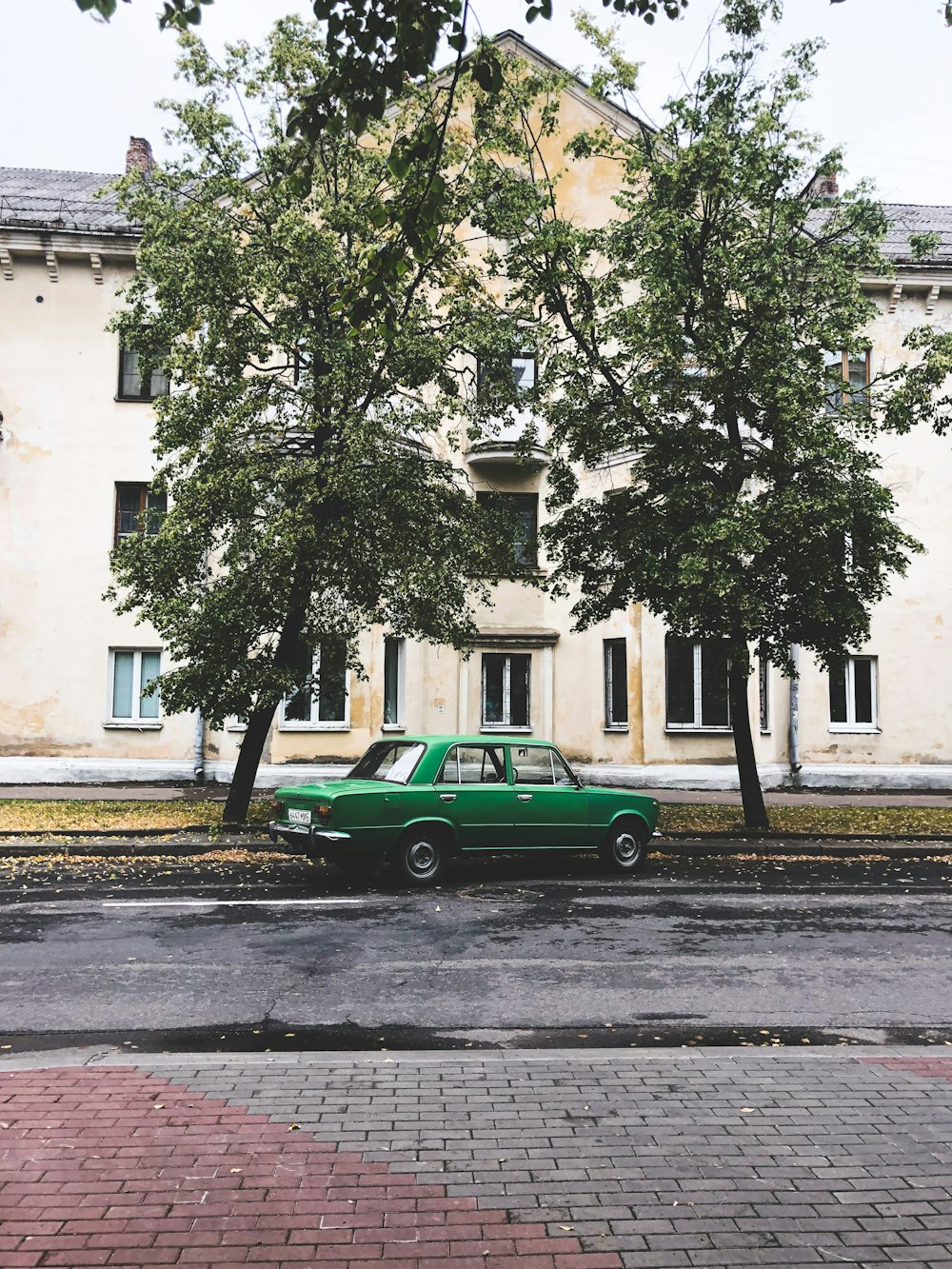 a green car parked in front of a large white building