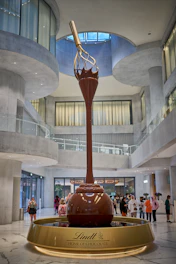 a large red and gold statue in a large building with people