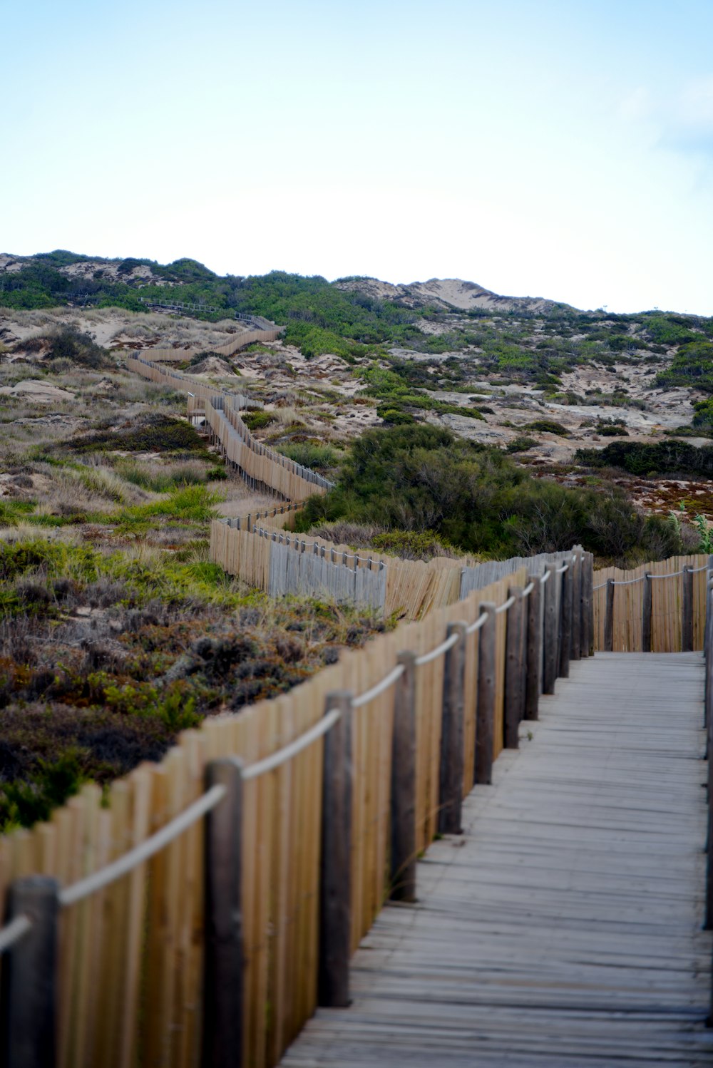 a wooden bridge over a grassy hill