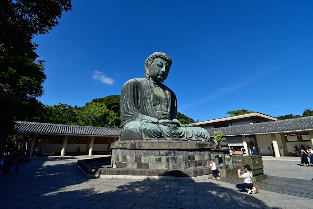 a statue of a man sitting on a bench in a courtyard