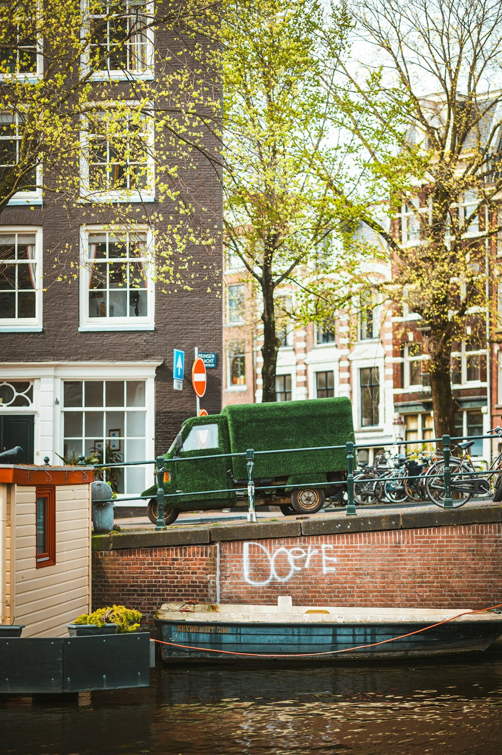 a green truck parked on the side of a canal