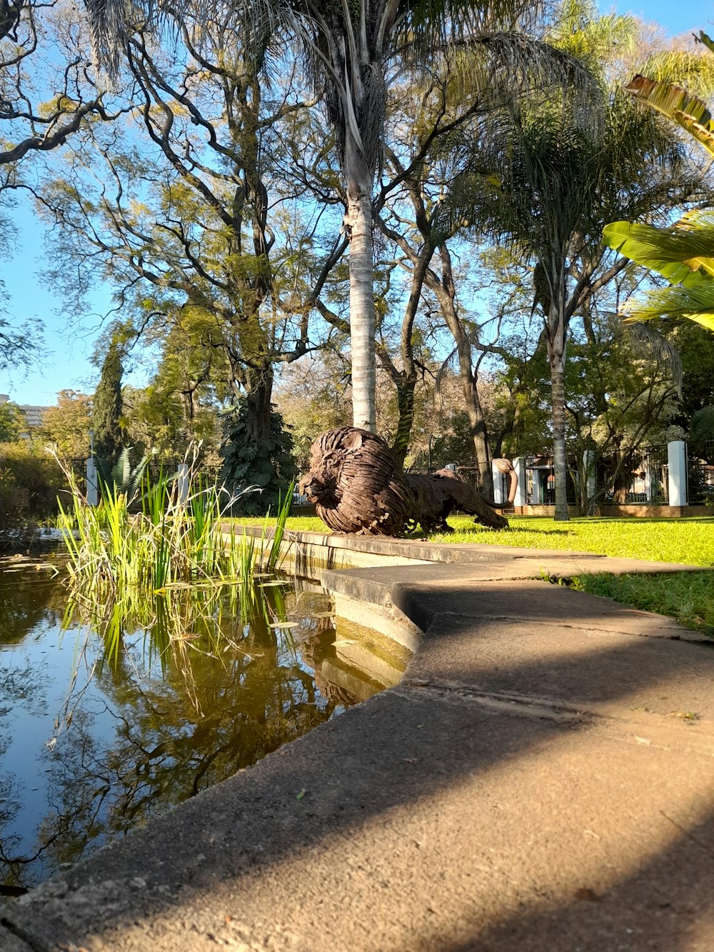 a statue of a dinosaur by a pond