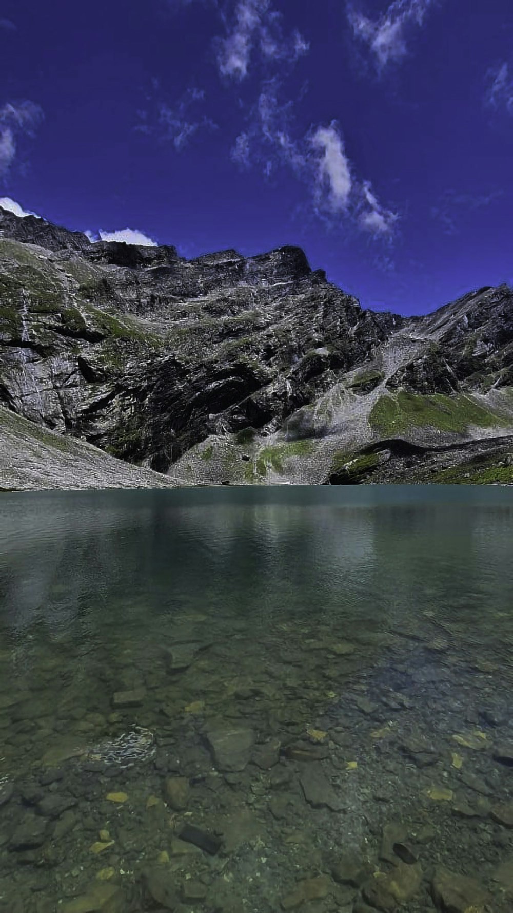 a body of water with a rocky mountain in the background