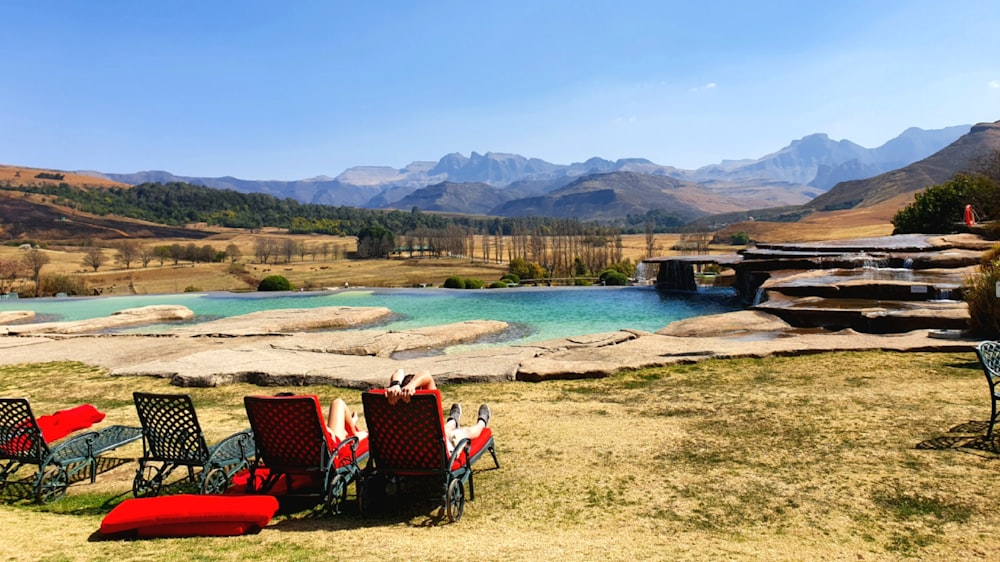 a group of chairs and a body of water with mountains in the background