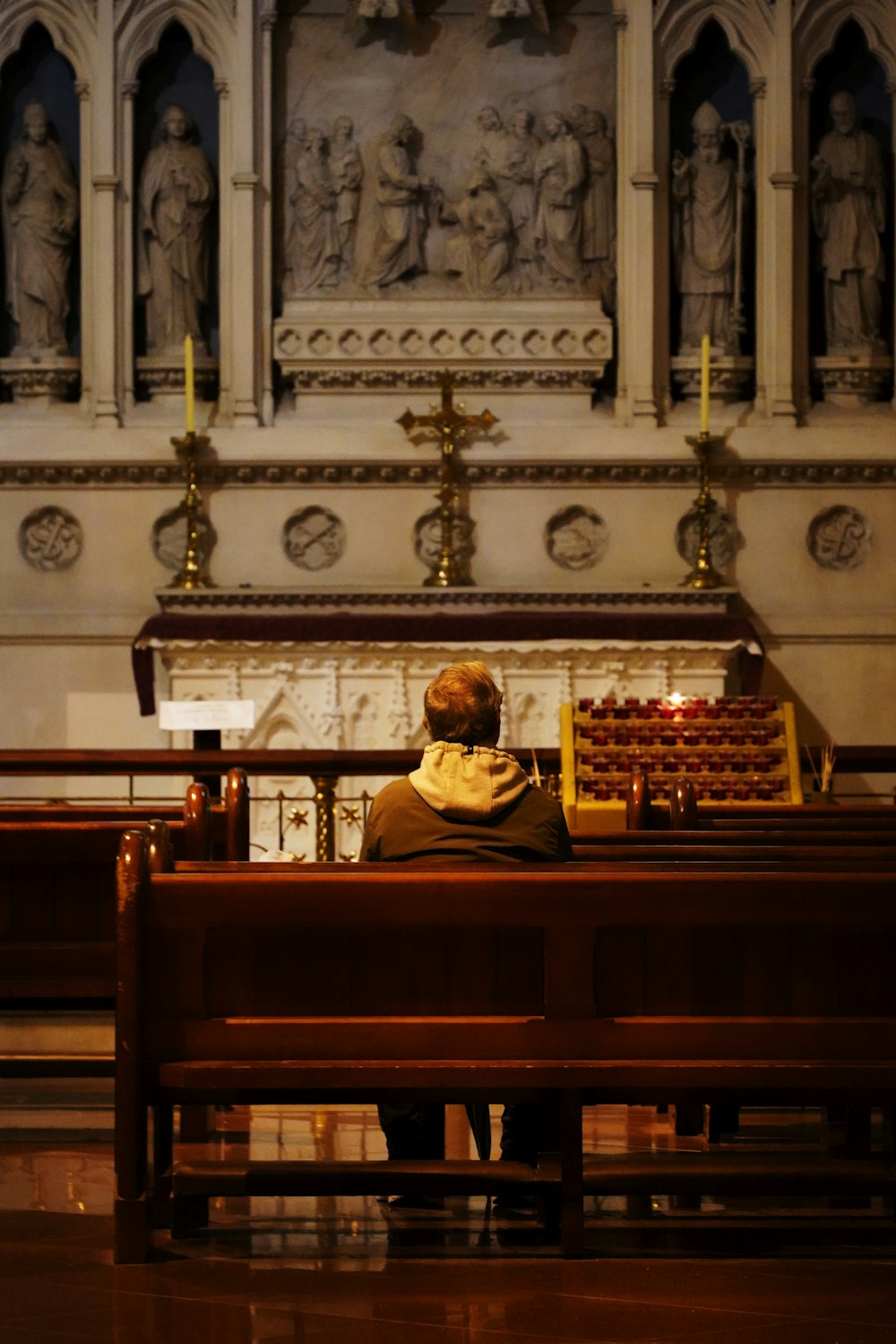 a person sitting at a desk in front of a wall with statues