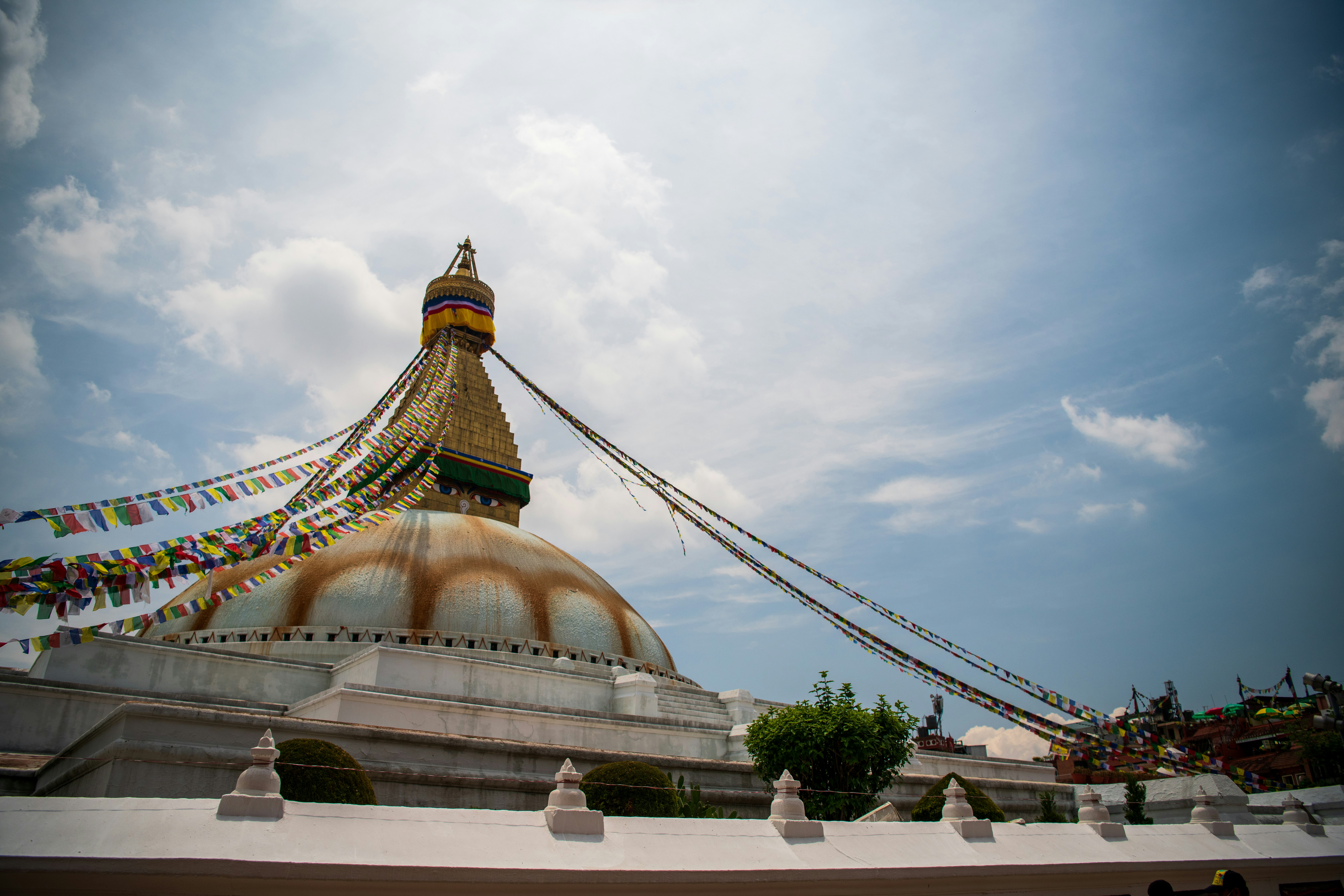 a large building with a large dome and a large gold tower with Boudhanath in the background
