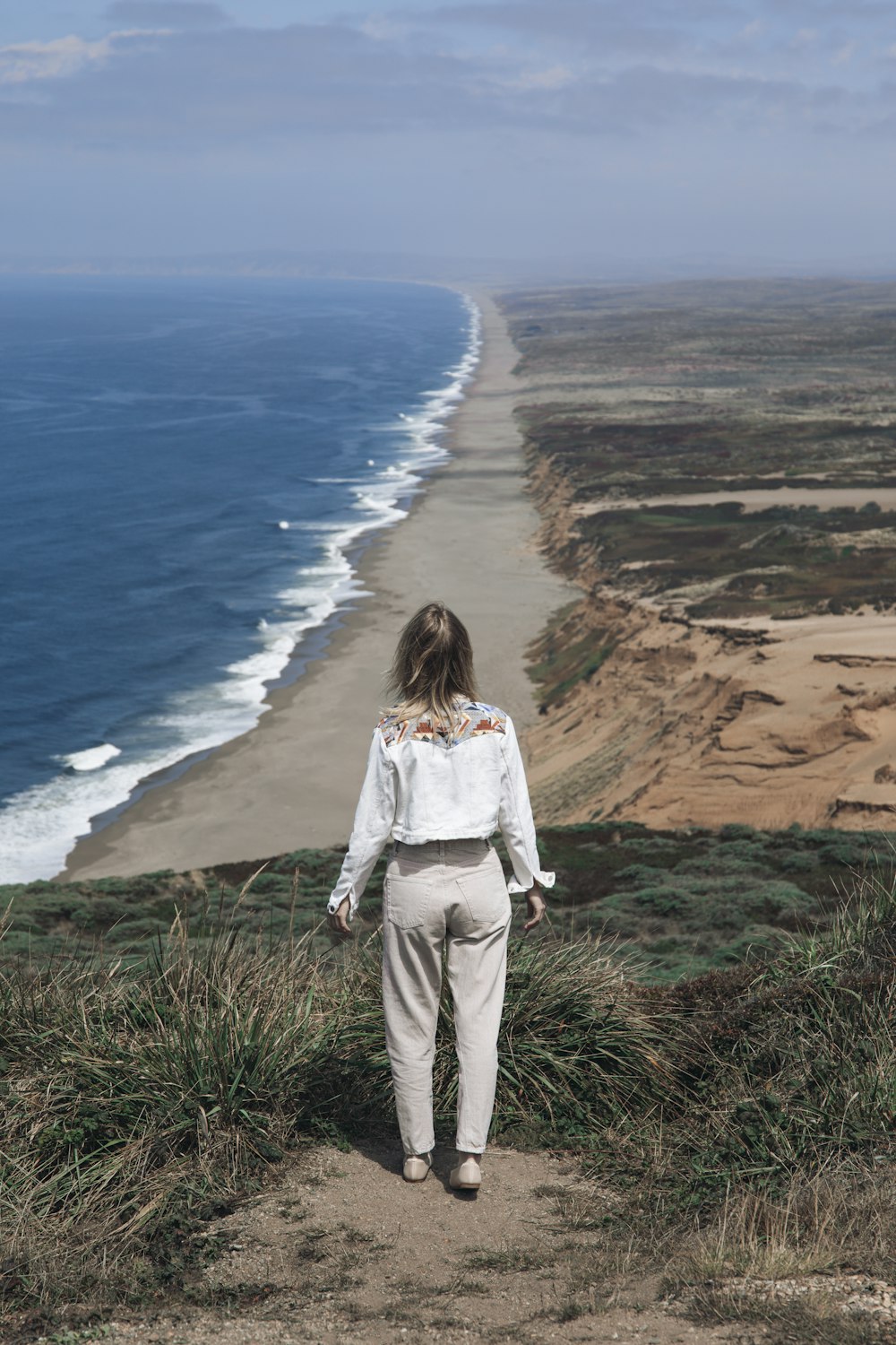 a person standing on a cliff overlooking a beach