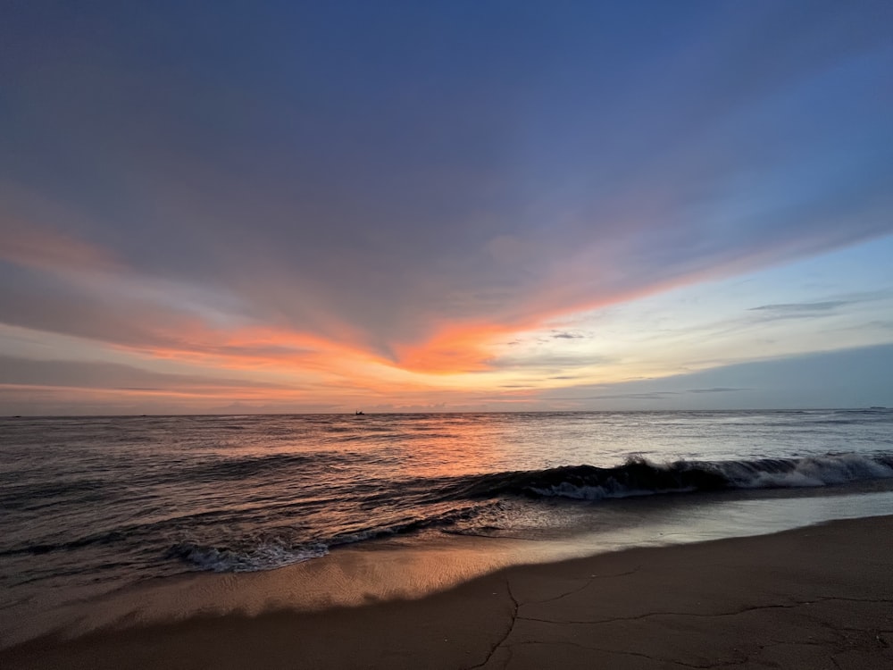 a beach with waves and a sunset