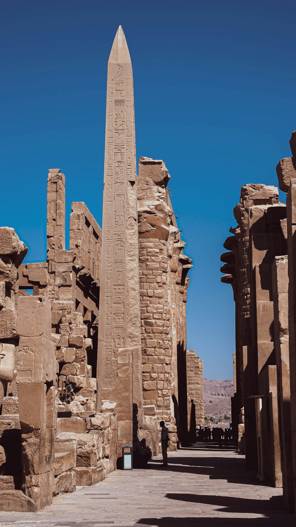 ein hoher Steinturm mit Karnak im Hintergrund