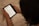 A person holding an e-reader displaying text from a book. The device is being read on a soft, beige surface, and the image focuses on the hands and the device.