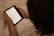 A person holding an e-reader displaying text from a book. The device is being read on a soft, beige surface, and the image focuses on the hands and the device.
