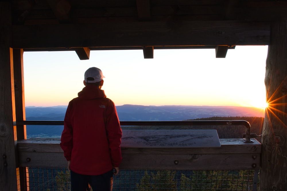 a person standing in front of a window looking out at the water