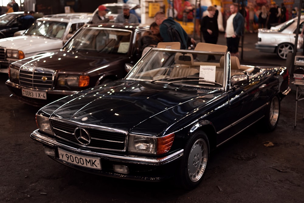 a black car parked in a showroom with other cars