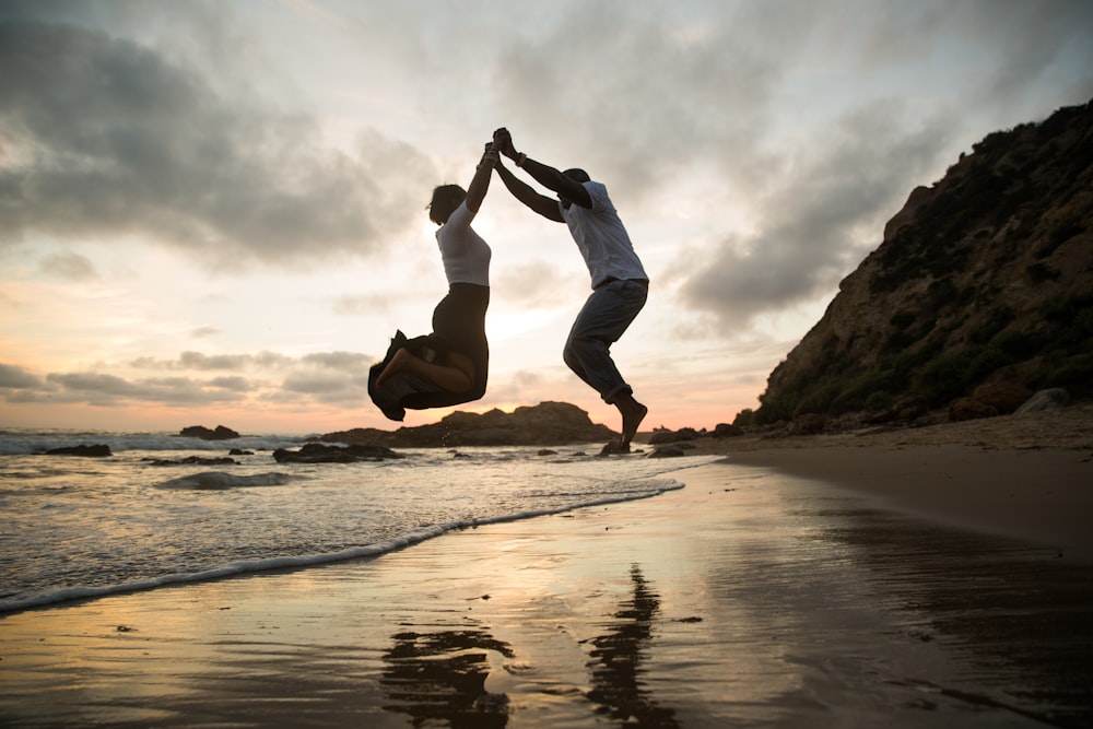 a man and a woman jumping on a beach