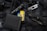 An assortment of tactical items lies on a black, molle backpack. The items include a black flashlight, a multi-tool, a folding knife, a black wallet, and a patch displaying the Ukrainian flag.