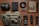 A neatly arranged collection of various items on a wooden surface, including a small first aid pouch, a black elastic band, a book resembling an old newspaper, a tactical pen, a wallet, a multitool, a flashlight, a folding knife, a rugged cellphone, and a green crossbody bag.