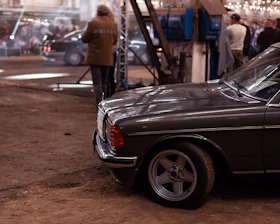 Elegant gala dinner setting with vintage cars parked nearby under warm lights.