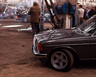 Classic car parked beside a rustic venue with string lights overhead.