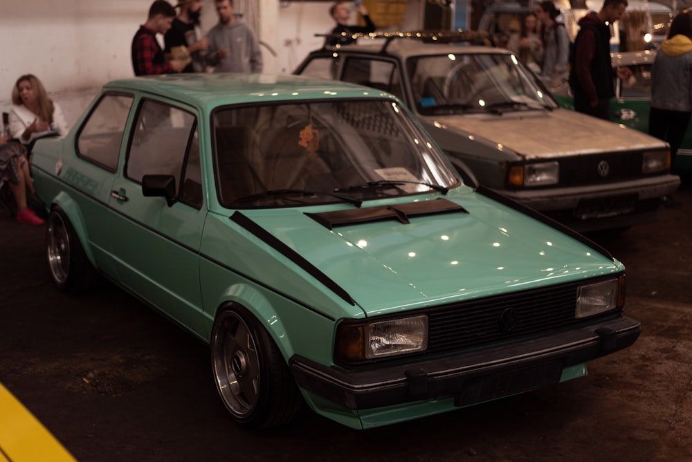 a green car parked in a showroom with other cars