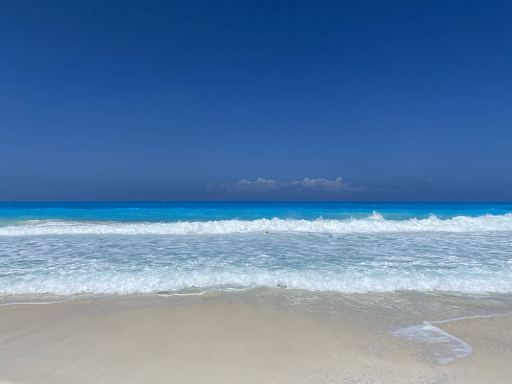 a beach with waves and a blue sky
