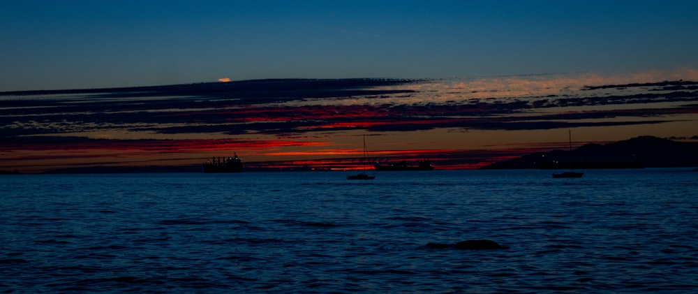 a body of water with boats in it and a sunset in the background