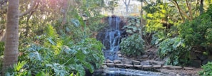 A serene backyard featuring a waterfall and ambient lighting.