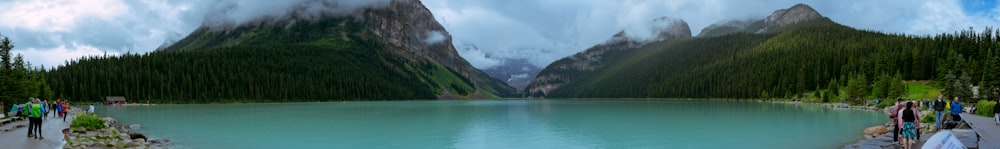 a body of water with people and mountains in the background