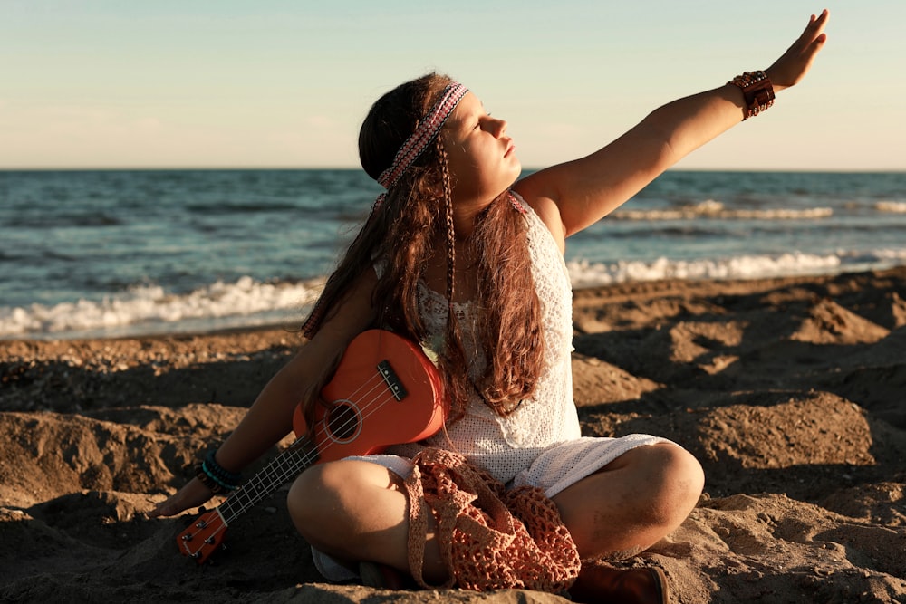 a person sitting on a beach playing a guitar