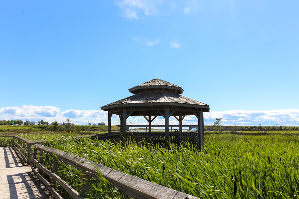 a wooden walkway leading to a gazebo in a grassy field