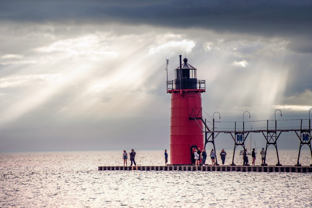 a group of people standing on a dock by a lighthouse