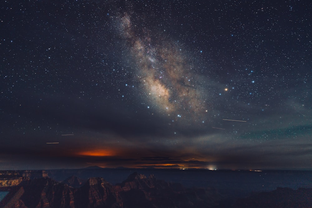 a night sky with stars and a mountain range