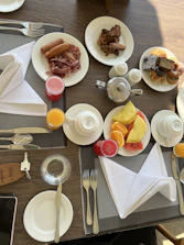 A breakfast table set with traditional Malaysian dishes and fresh fruit.