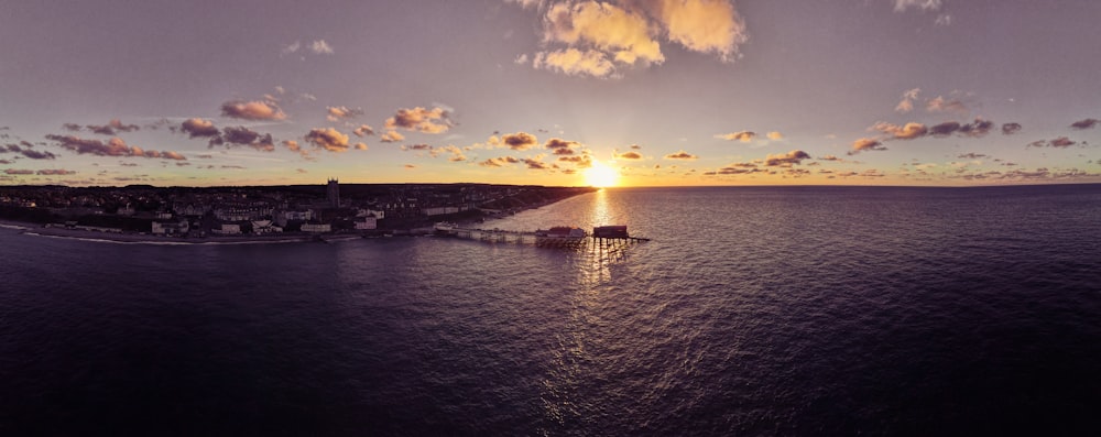 a body of water with a building and a sunset in the background