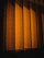 Patterned curtains illuminated by a warm light, casting shadows that create a sense of depth and texture.