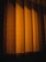 Patterned curtains illuminated by a warm light, casting shadows that create a sense of depth and texture.